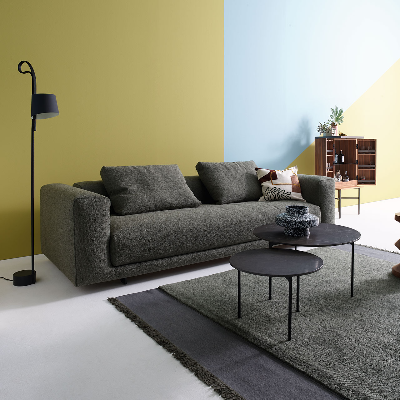 Sofa aus grauem Stoff mit zwei Sting-Tischen davor.