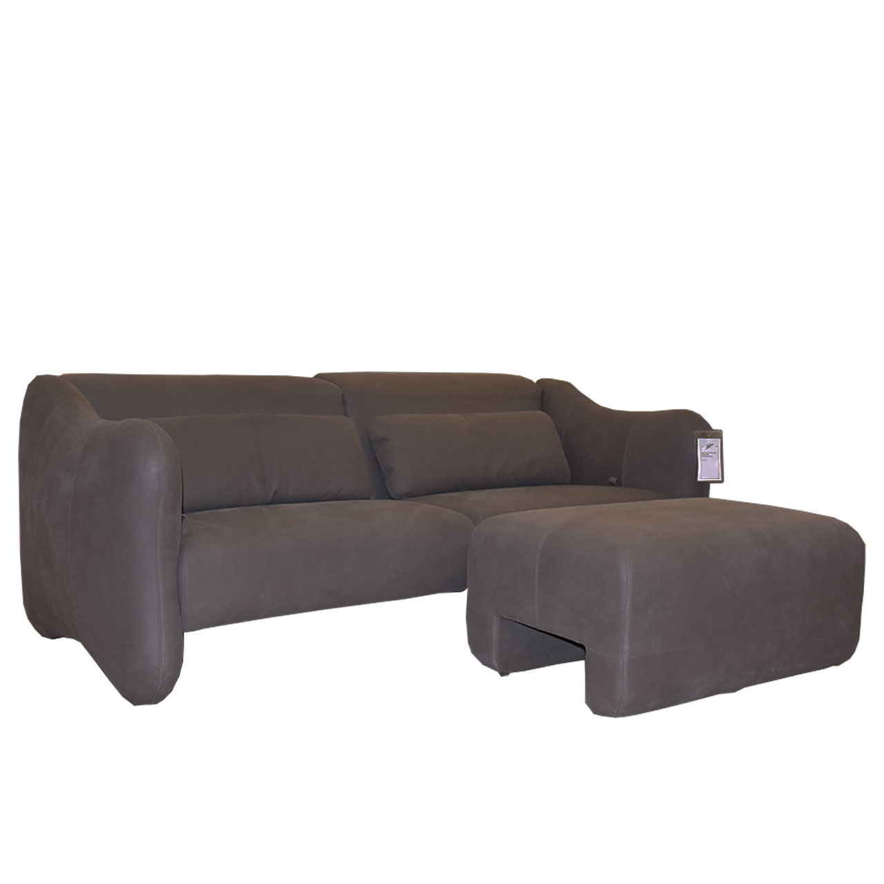 Sofa mit 3 Sitzen und zwei länglichen Rückenkissen in dunkelbraunem Leder. Davor steht ein passender Hocker.