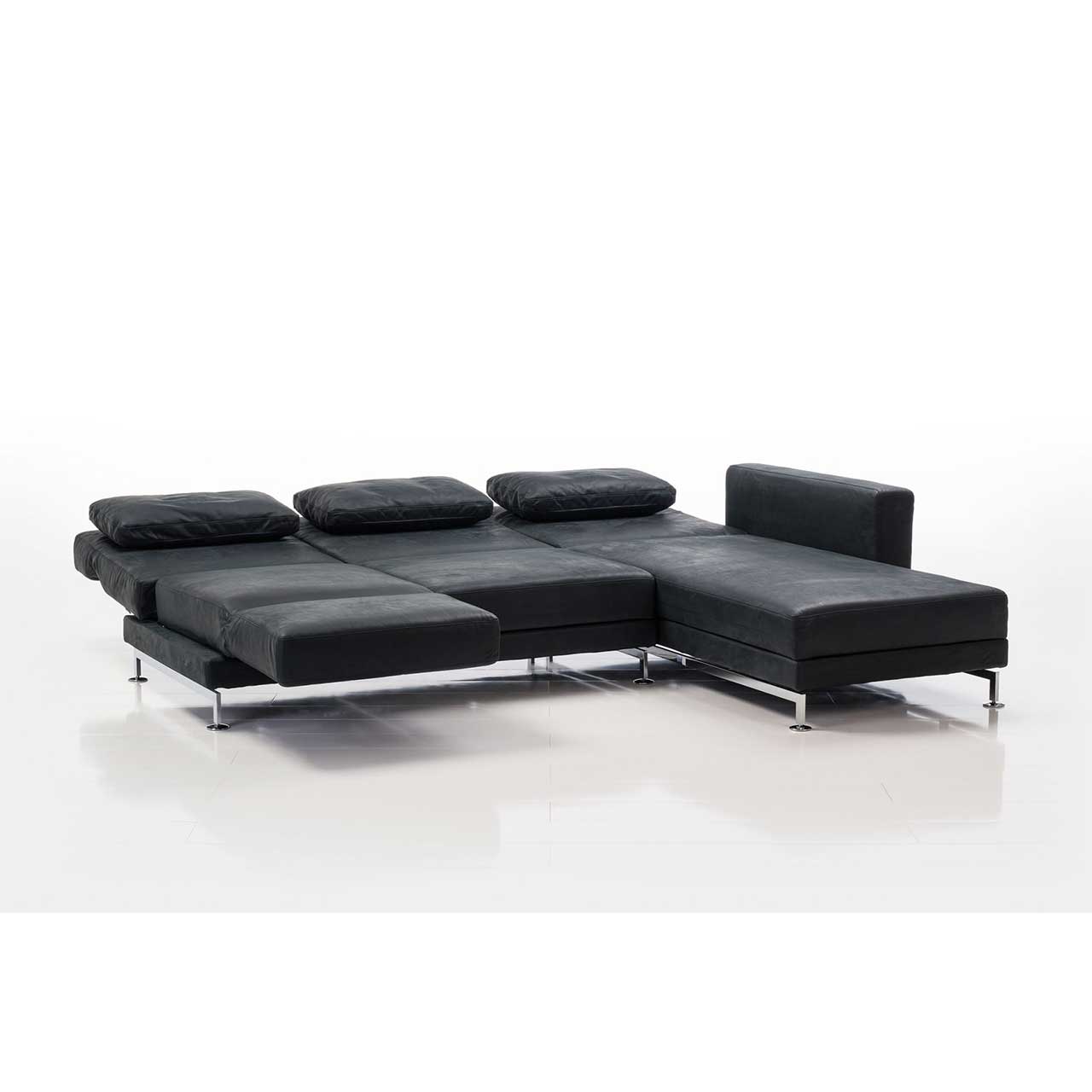 Eckgarnitur in schwarzem Leder mit Longchair rechts. Der Sitzplatz ganz rechts ist zur Relaxliege umgebaut. Alle Rückenlehnen sind in die Waagrechte abgesenkt.