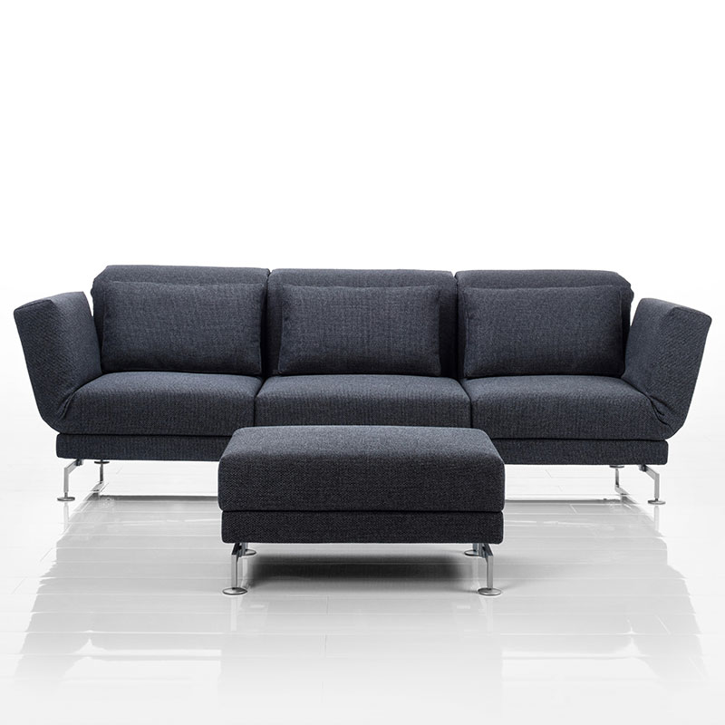 Sofa mit drei Sitzplätzen in dunkelgrauem Stoff. Vor dem mittleren Sitzplatz steht ein passender Hocker.