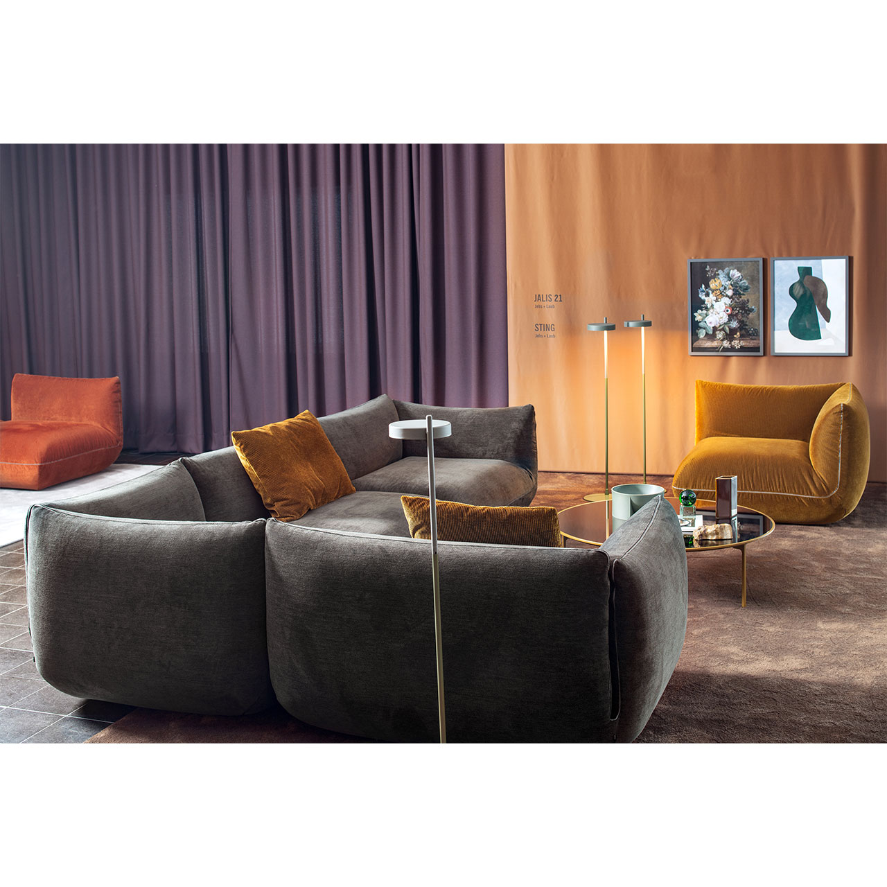 Eckgarnitur aus dunklem Stoff und im Hintergrund Sesselelement aus bernsteinfarbenem Stoff