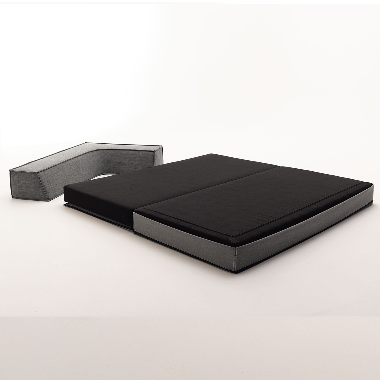 Das Schlafelement ist aufgeklappt, man sieht die schwarze Liegefläche. Das Rückenelement liegt daneben.