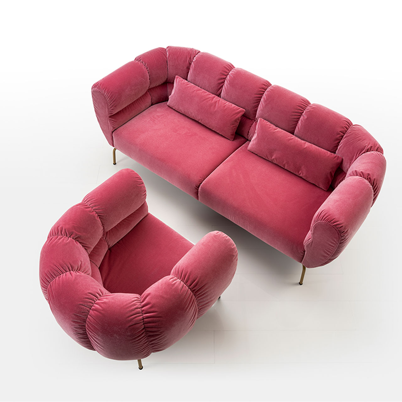 Ensembke aus Sofa und Sessel von brühl magnolia. Das Bild wurde von oben aufgenommen. Beide Möbel sind mit einem roten Stoff bezogen. Die Füße sind golden.