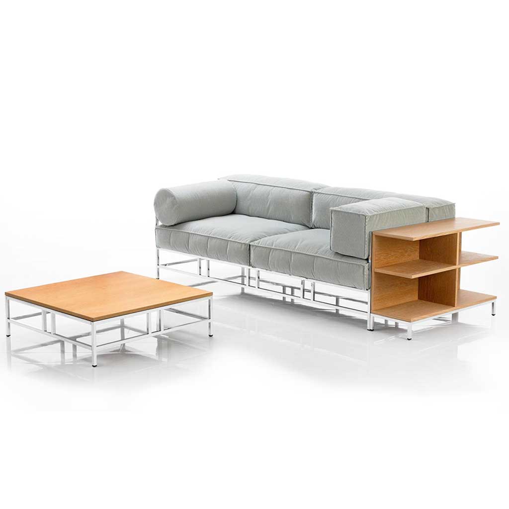 Sofa mit Polstern in hellem mint und chrom glänzendem Untergestell. Rechts neben dem Sofa ist ein niedriges, offenes Regal an das Sofa angestellt.