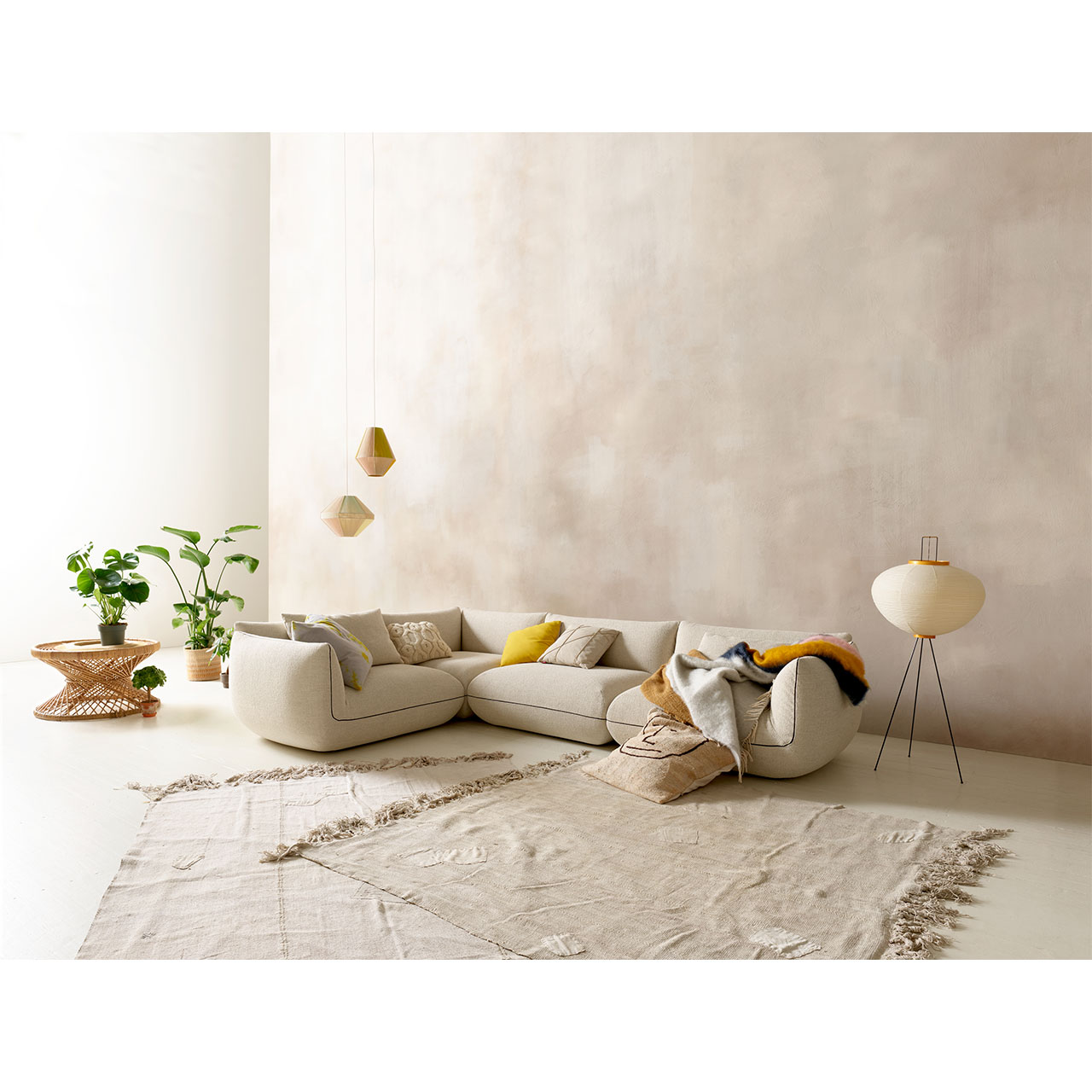 Eckgarnitur aus hellem Stoff mit Dekoration in einem Wohnzimmer