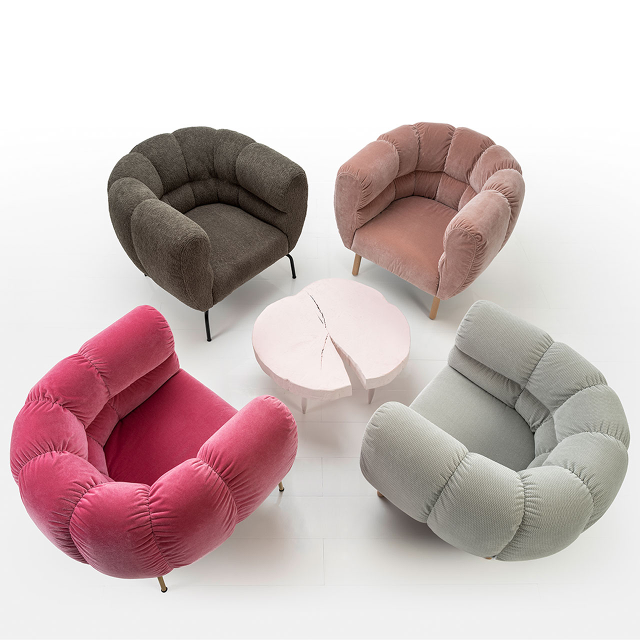 Vier Sessel der Serie brühl magnolia sind um einen runden Tisch mit Tischplatte aus einer Baumholzscheibe gruppiert. Das Bild ist von schräg oben fotografiert. Die Sessel haben die Farben rot, dunkelbraun, hellbraun und grau.
