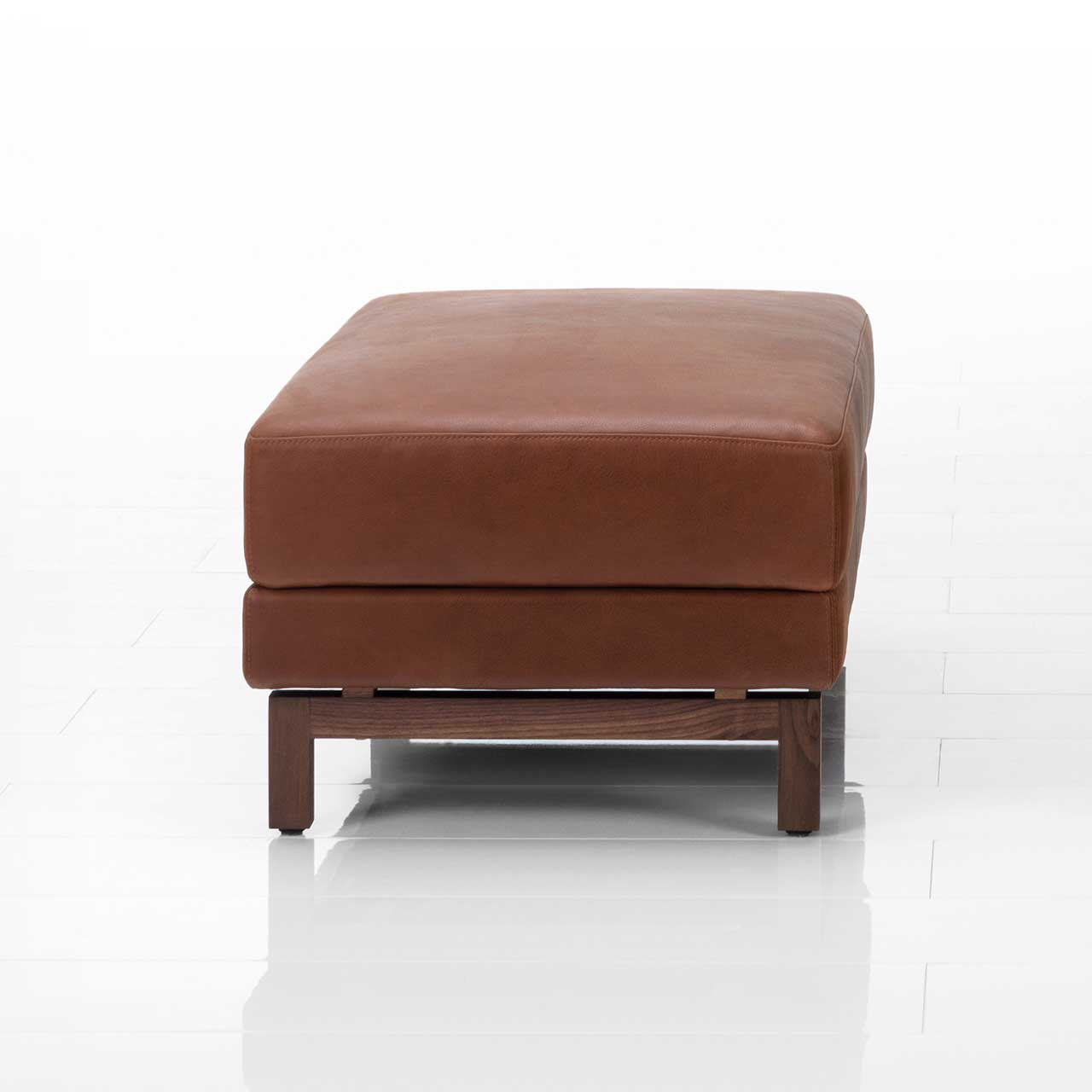 Schmaler Hocker mit braunem Lederbezug und Holzkufen.