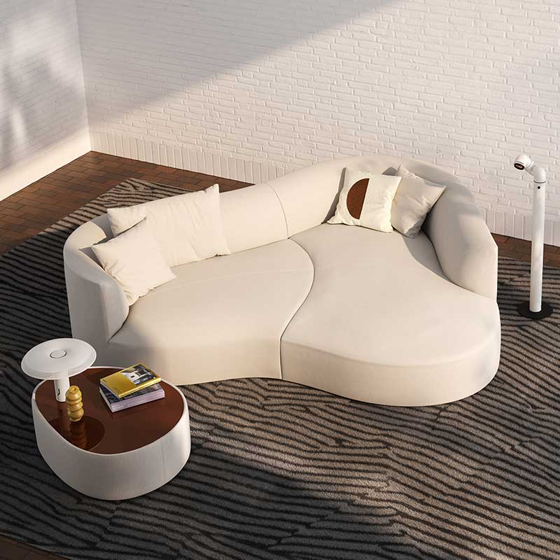 Organisch geformtes Sofa mit hellem Stoffbezug, Kissen und passendem Beistelltisch.