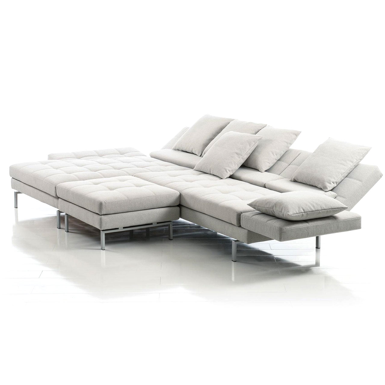 Graue Eckgarnitur mit breitem Longchair links und vor den mittleren Sitzplatz gestelltem Hocker..