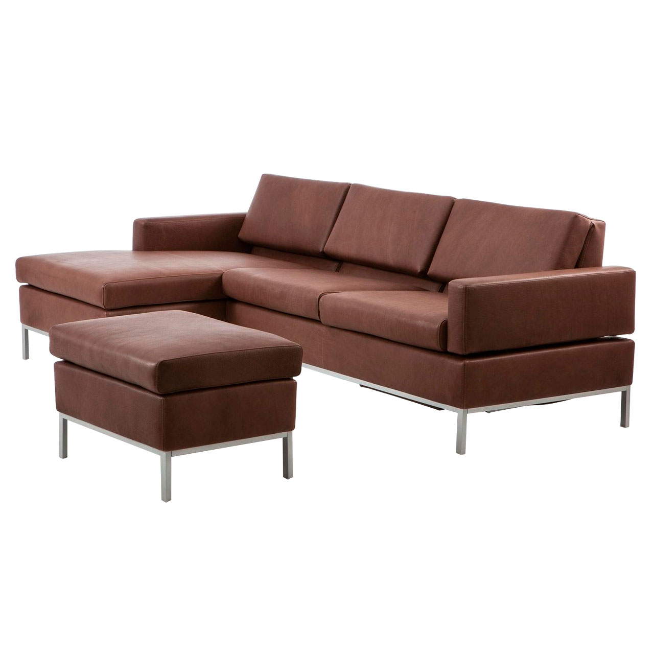 Leicht schräge Sicht auf eine dunkelbraune Ledergarnitur mit Longchair links und Anstellsofa rechts. Vor der Garnitur steht ein Hocker.