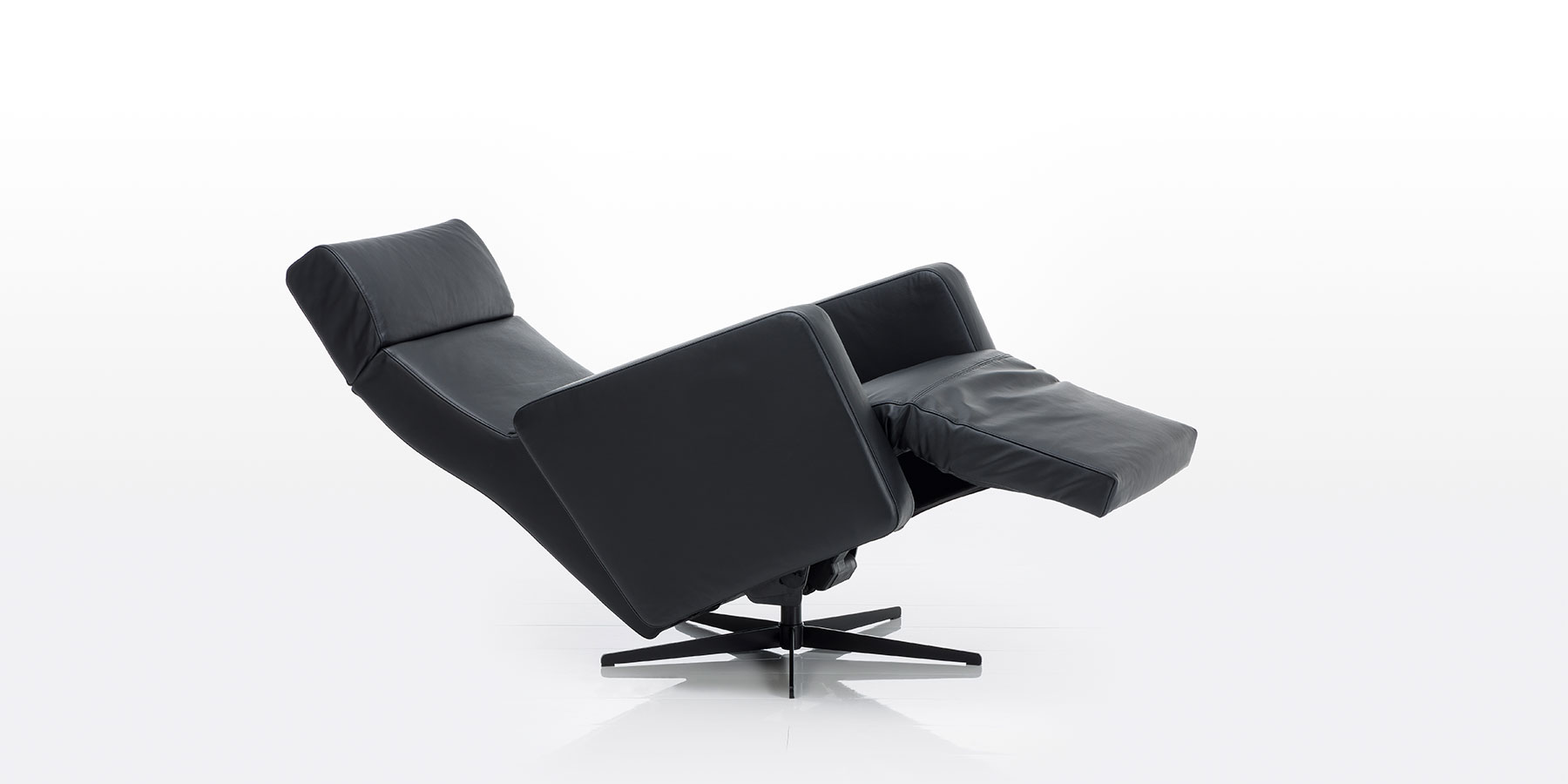 Elektrischer Relaxsessel mit Drehbasis in schwarzem Leder. Der Sessel ist in Liegeposition abgesenkt.