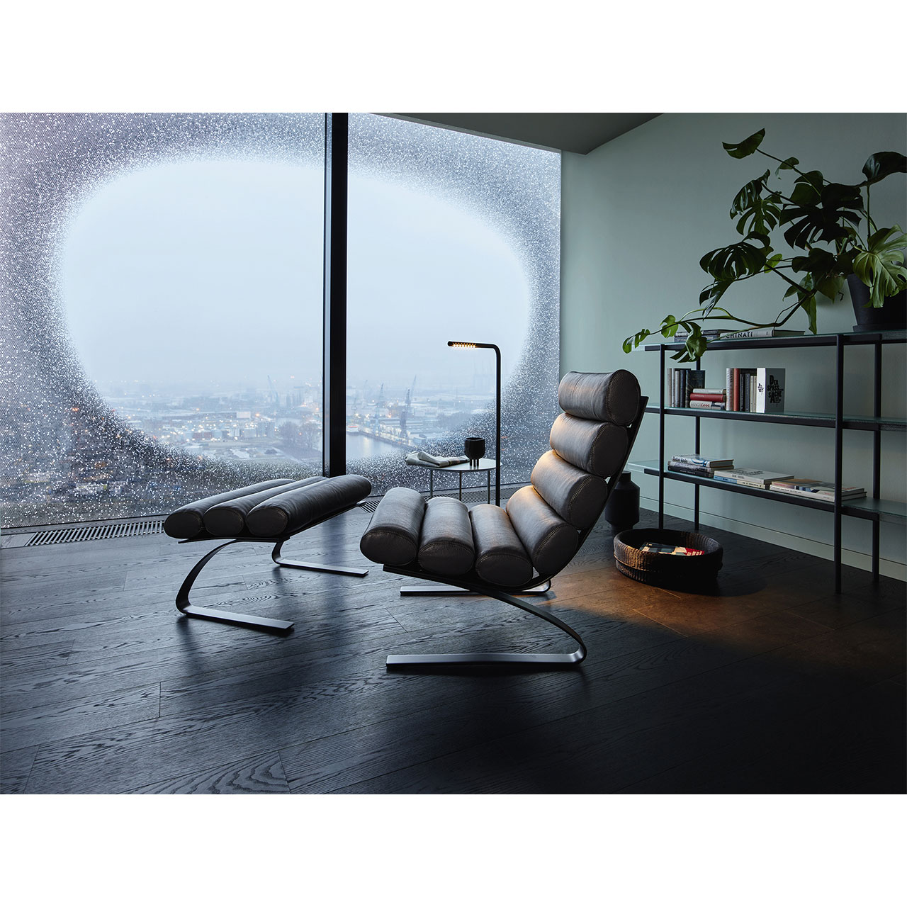 Sessel und Hocker in einem Wohnzimmer mit großem rundem Fenster