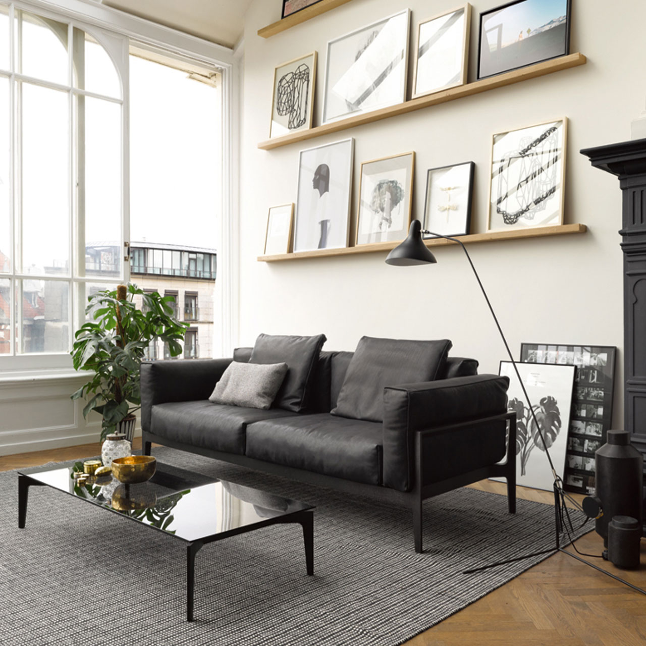 Schwarzes Ledersofa mit passenden Kissen, davor der passende Couchtisch aus Rauchglas.