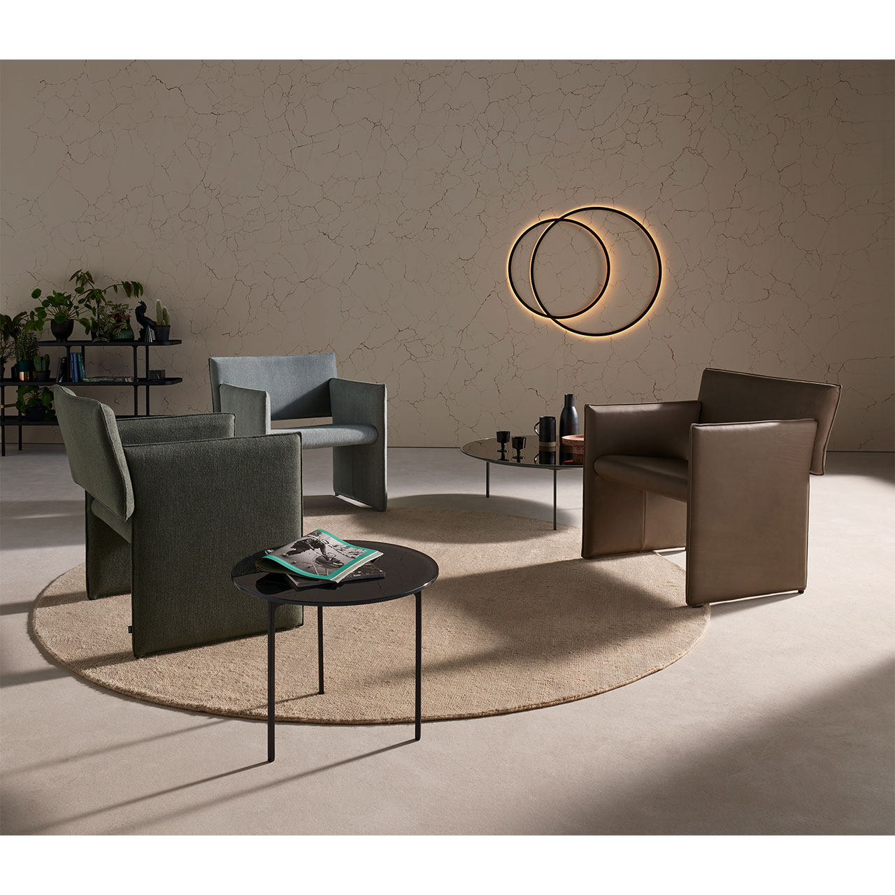 Drei Noto Sessel stehen auf einem runden Teppich in Wohnzimmer-Atmosphäre