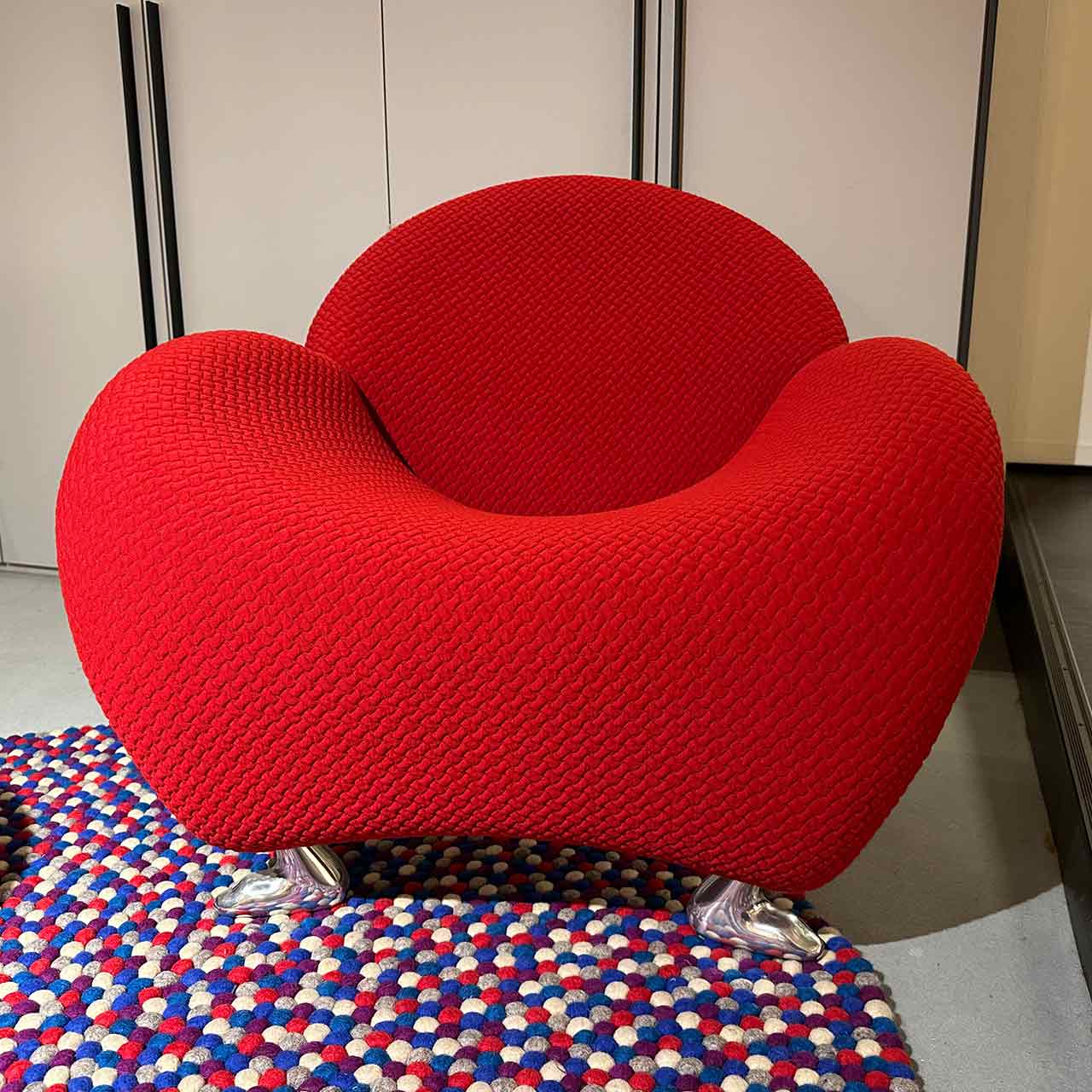 In der Frontalaufnahme sieht der Sessel rund aus wie ein Raumschiff. Unten sind chromfarbene Tierfüße sichtbar.