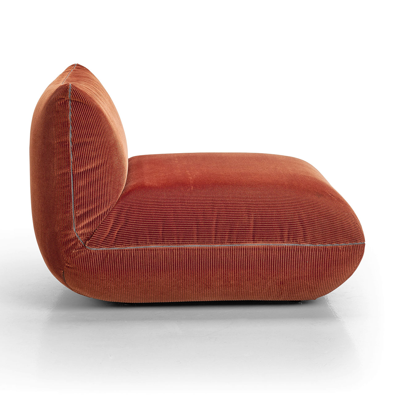 Das kleine Element ohne Armlehnen von der Seite aufgenommen. Orangebrauner Cord.