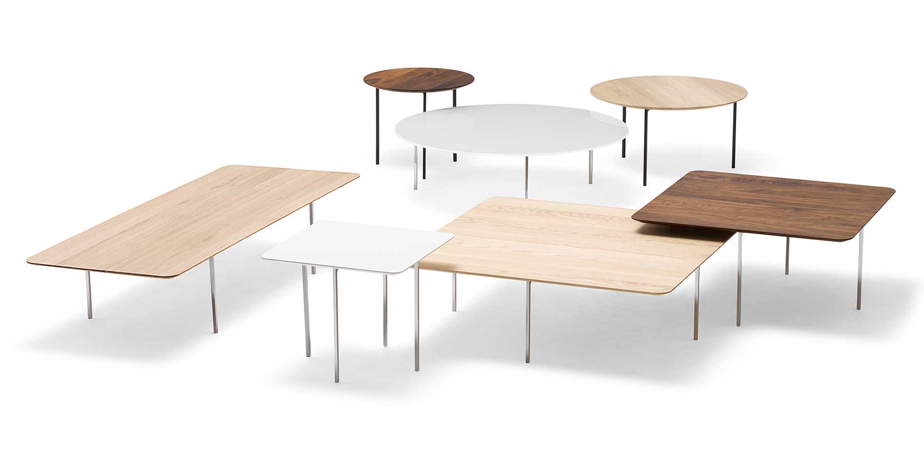 Vorne vier Tische mit eckigen Platten, hinten drei Tische mit runden Platten, verschiedene Größen und Materialien.