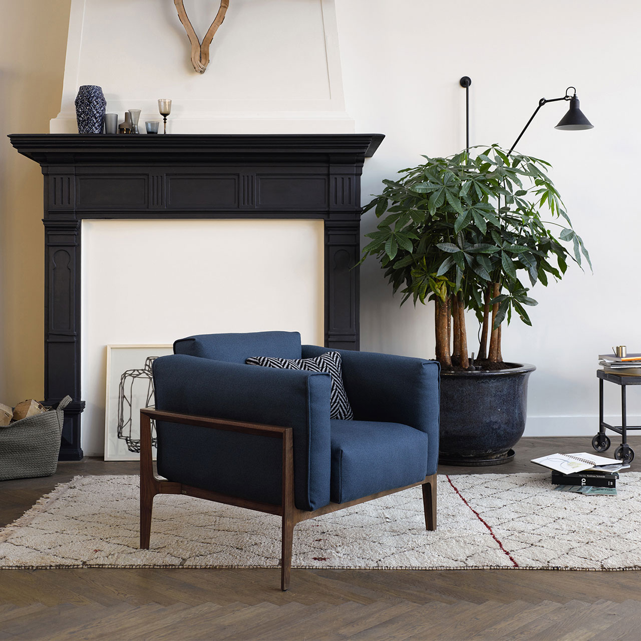 Sessel mit blauem Stoffbezug und Deko-Kissen in einem Wohnzimmer vor dem Kamin
