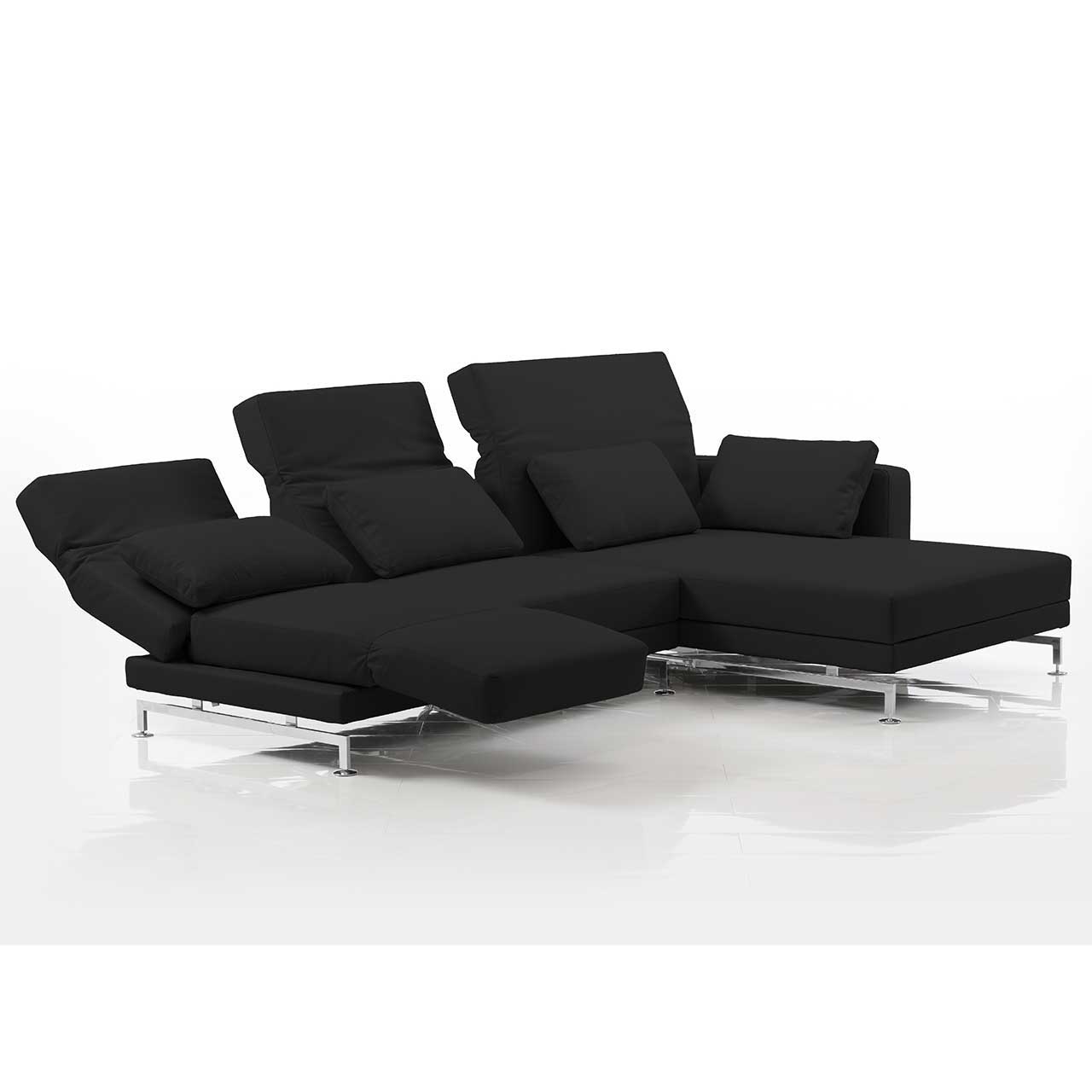 Eckgarnitur mit breitem Longchair rechts in schwarzem Stoff. Die mittlere und linke Rückenlehne sind teilweise abgesenkt. Die linke Armlehne ist zur Fußstütze vorgeschwenkt.