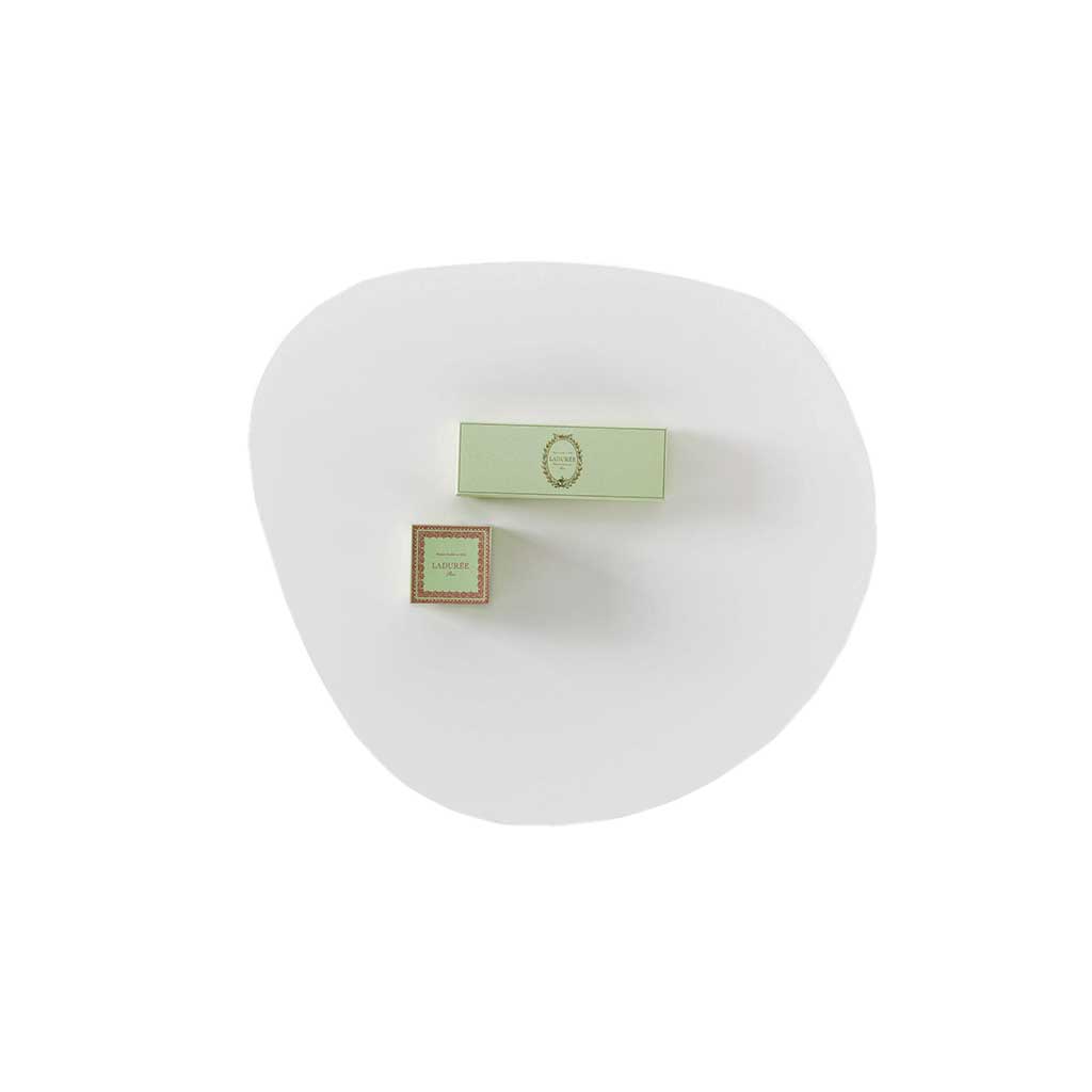 Sicht auf eine weiße, ungleichmäßig rund geformte Tischplatte. Darauf liegen zwei hellgrüne, rechteckige Gegenstände.