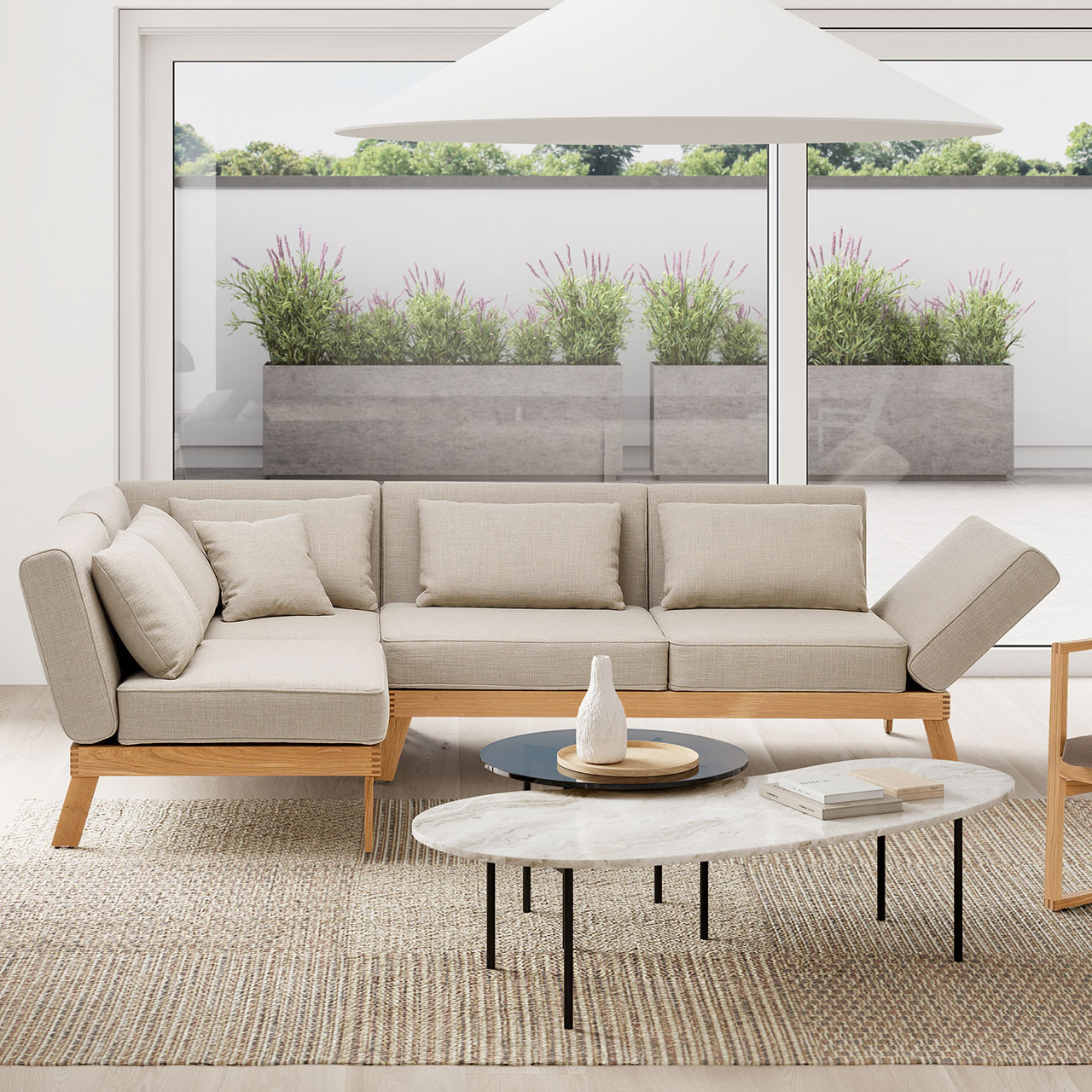 Ambientebild. Eine Eckgarnitur der Serie brühl lofoten lounge steht vor einem bodentiefen Fenster. Der Blick geht auf eine Terrasse.