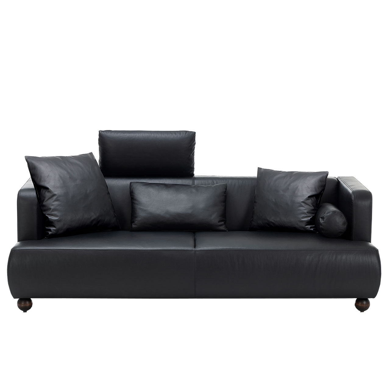 Schwarzes Ledersofa von brühl aoyama mit vier Kissen und einer Kopfstütze am linken Sitzplatz. Die schwarzen Holzfüße sind wie Kugeln geformt.