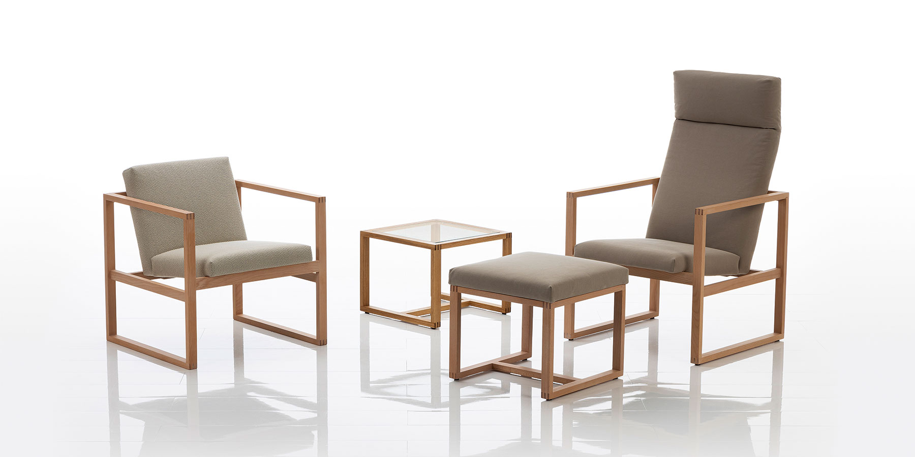 Ein Hochlehnsessel und ein Sessel mikt niedriger Lehne mit filigranem Holzrahmen und Stoffbezügen.