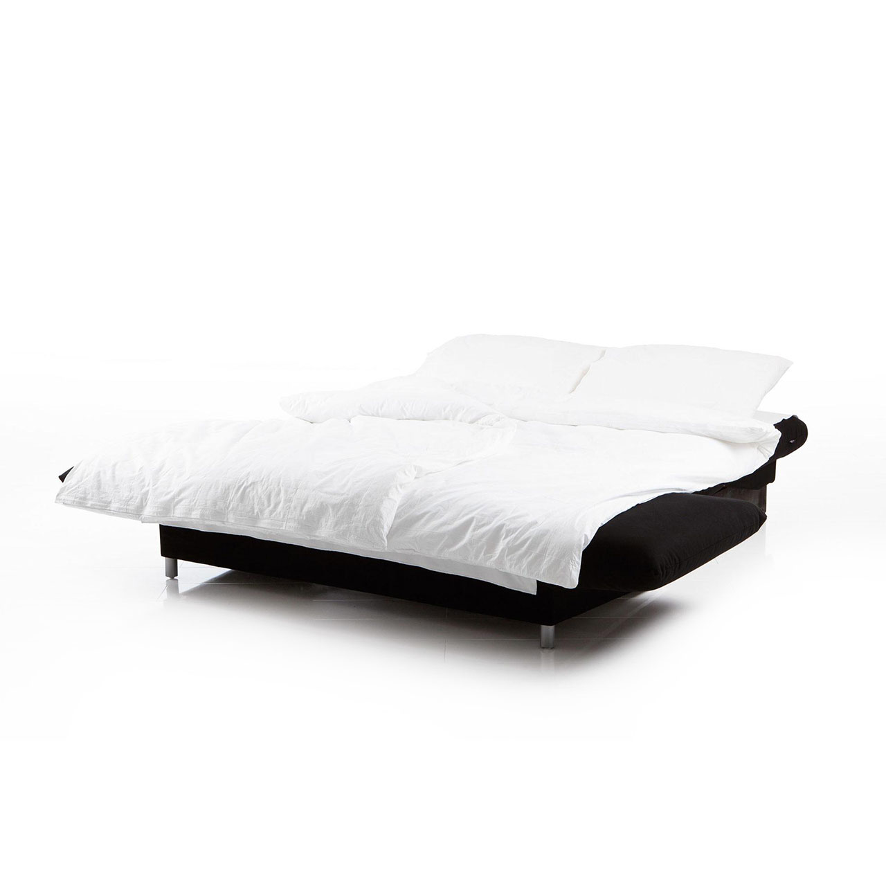 Ein zu einer Liegefläche ausgeklapptes Bettsofa in einem schwarzen Stoff mit weißer Bettwäsche.