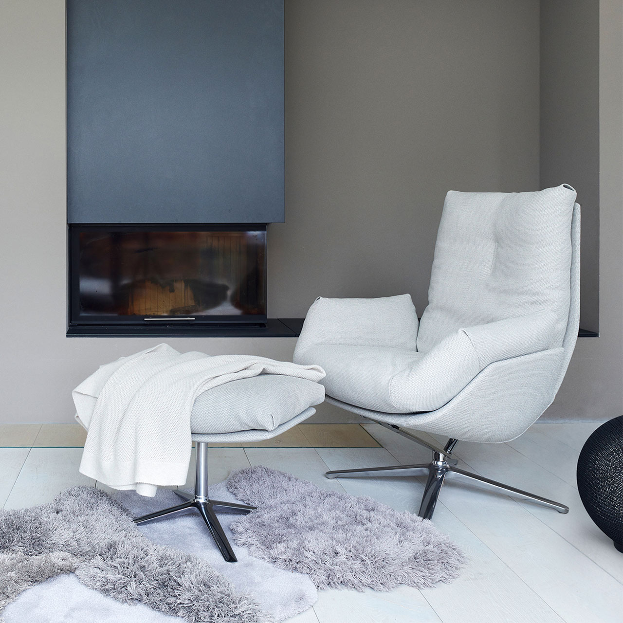 Loungesessel mit weißem Bezug und passendem Hocker in einem Wohnzimmer