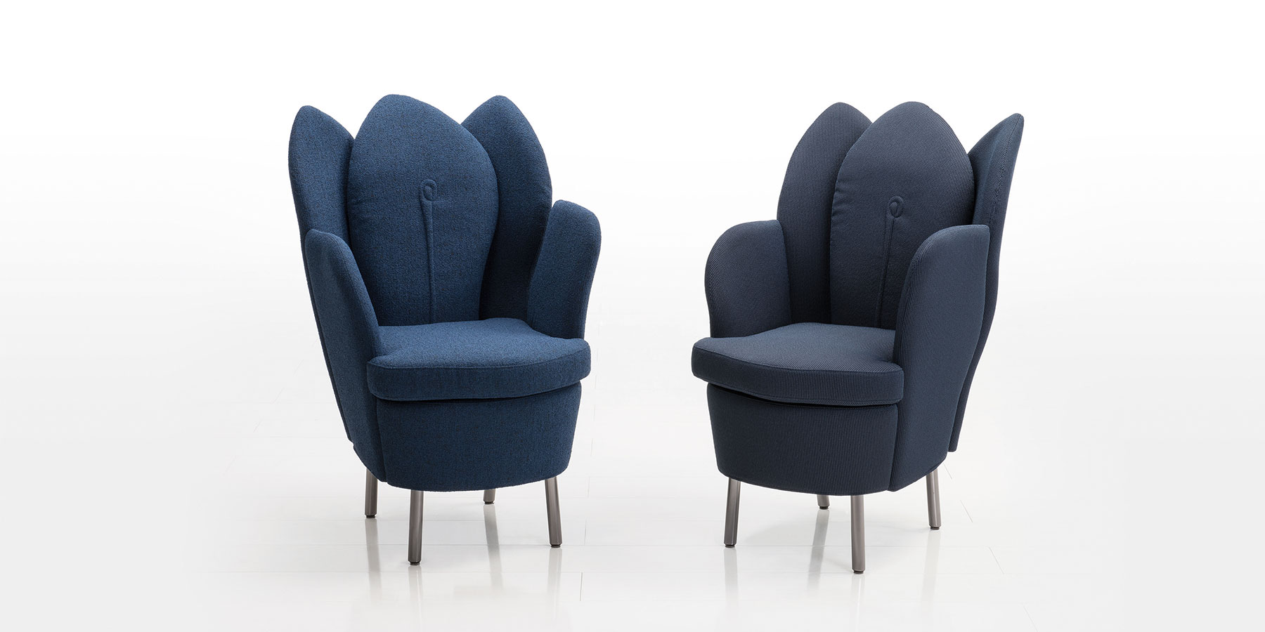 Zwei Sessel mit dunkelblauem Stoff. Die Rückenlehne besteht aus drei überlappenden Blattsegmenten, so dass die Sessel an Blütenkelche erinnern.