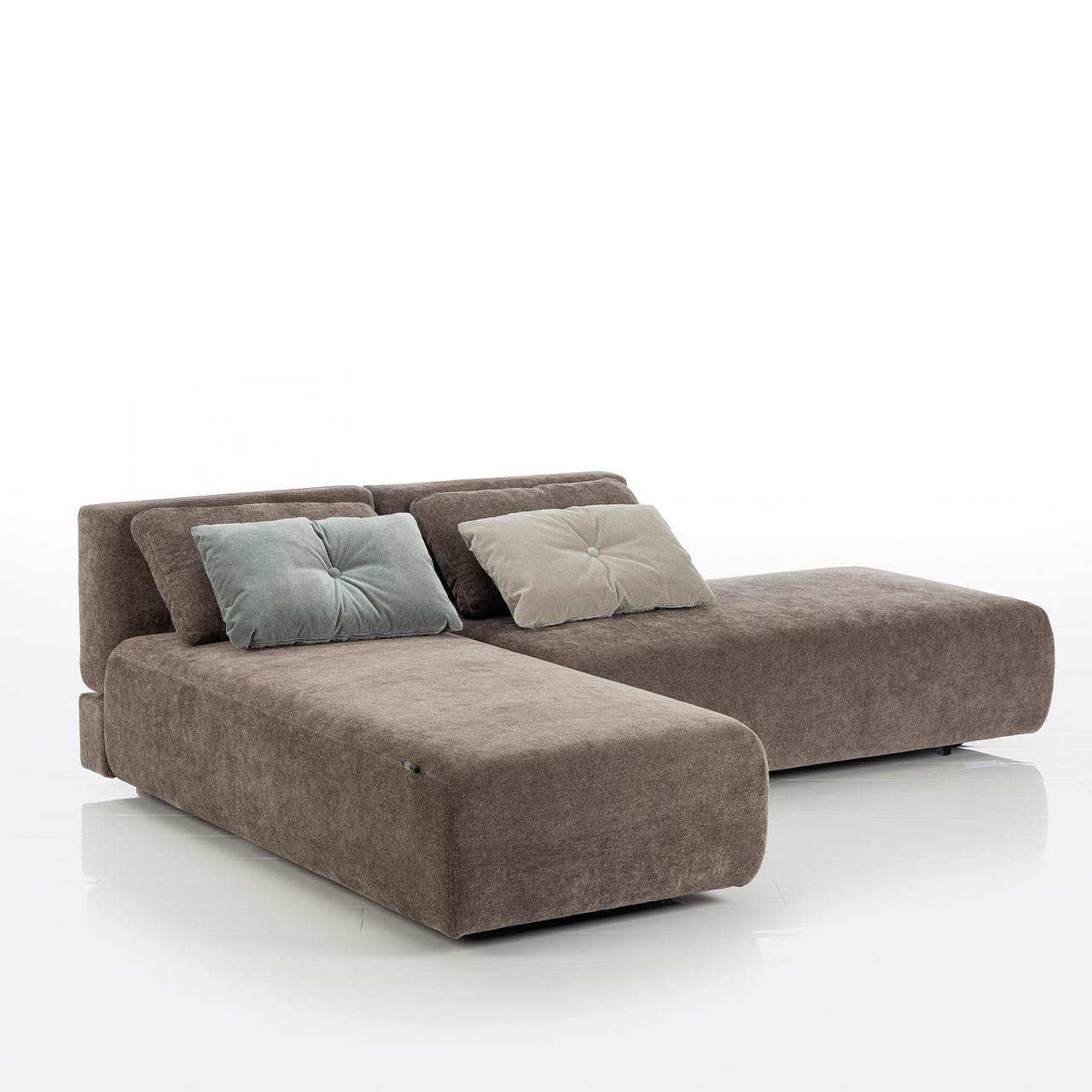 Bodennahes braunes Eckofa mit Drehsofa links und Longchair rechts. Auf dem Sofa liegen zwei eckige Kissen.
