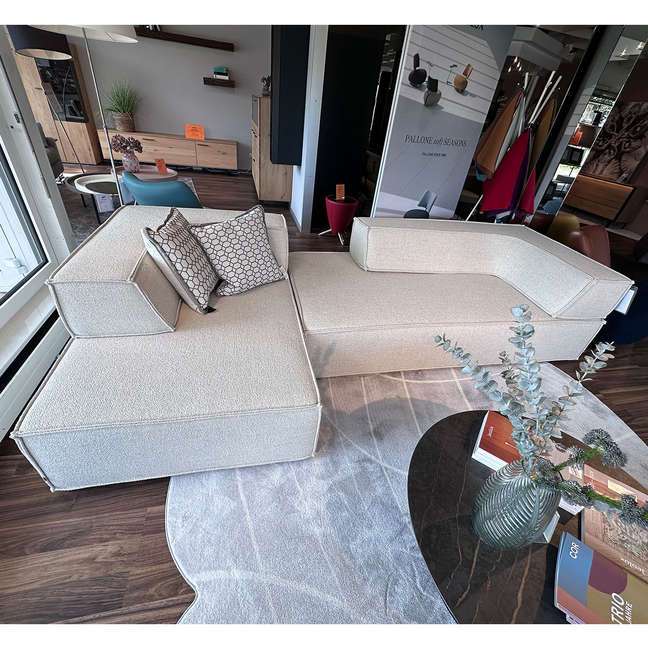 Weißes Sofa bestehend aus zwei rechteckigen Sitzelementen und zwei eckigen Rückenteilen, dekoriert mit Kissen.