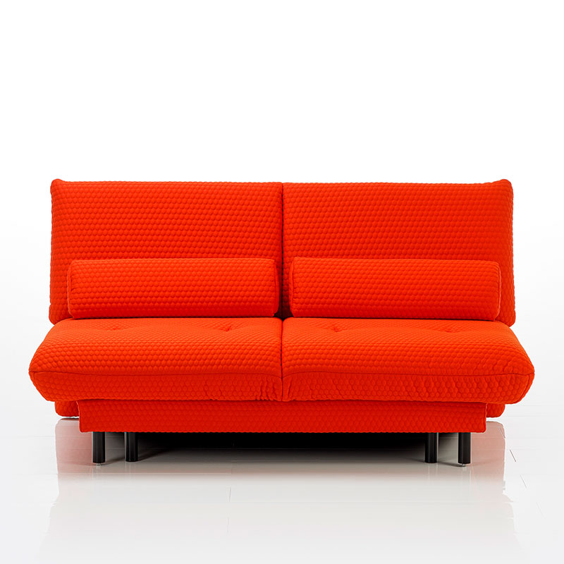 Orange-rotes Sofa, dass in seiner Kontur an einen Futon erinnert.