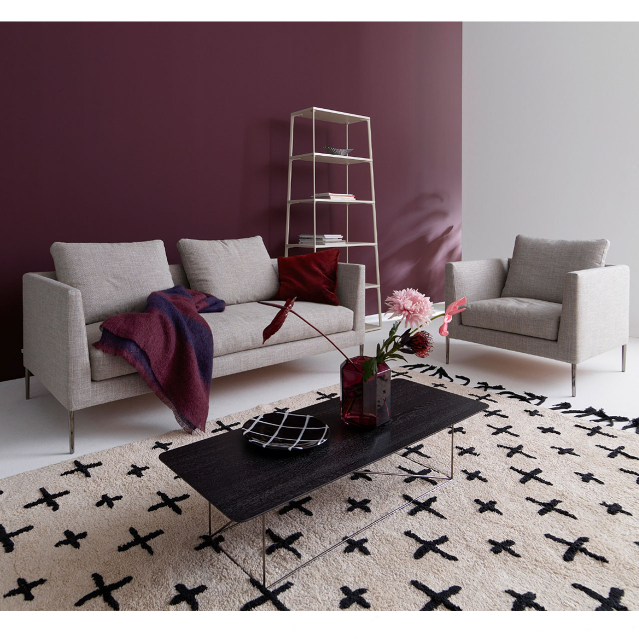 Graues Zweisitzer Sofa links, rechts ein Sessel, davor ein Couchtisch