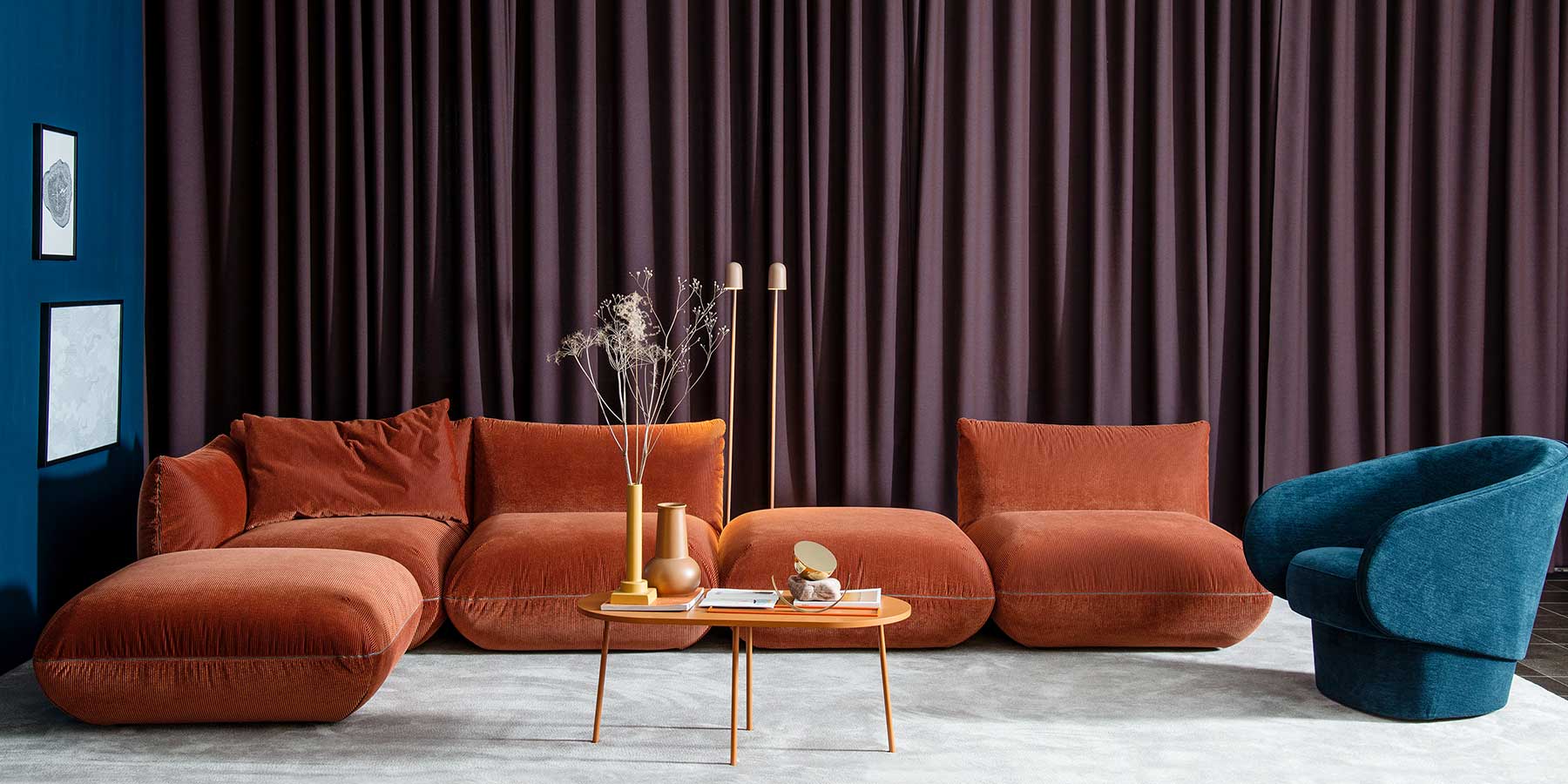 Jalis Sofa bestehend aus fünf Elementen in rötlichbraunem Cord-Stoff, rechts ein blauer Sessel, davor ein Couchtisch