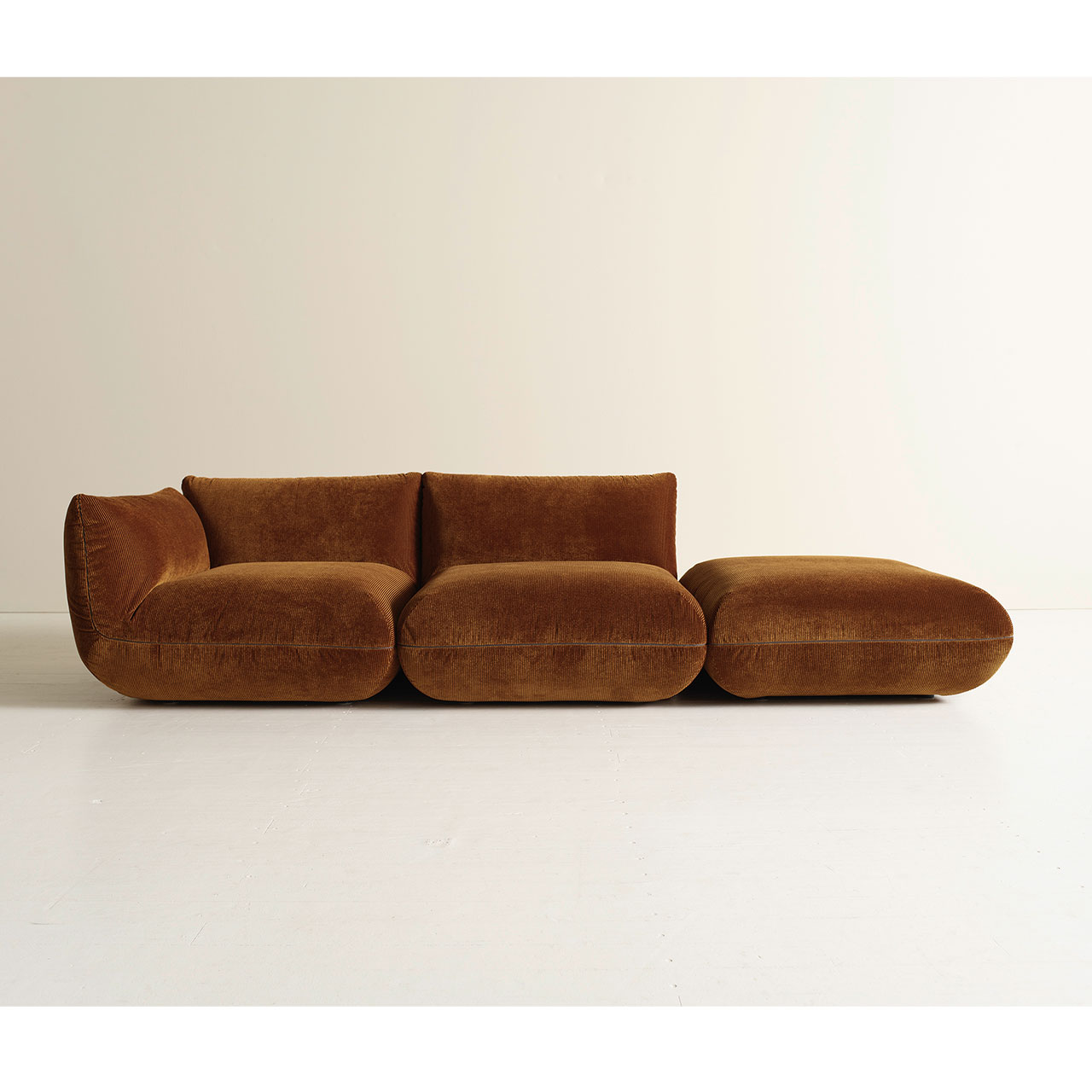 Sofa aus bernsteinfarbenem Cord bestehend aus drei Teilen. Lehne links, rechts Hocker.