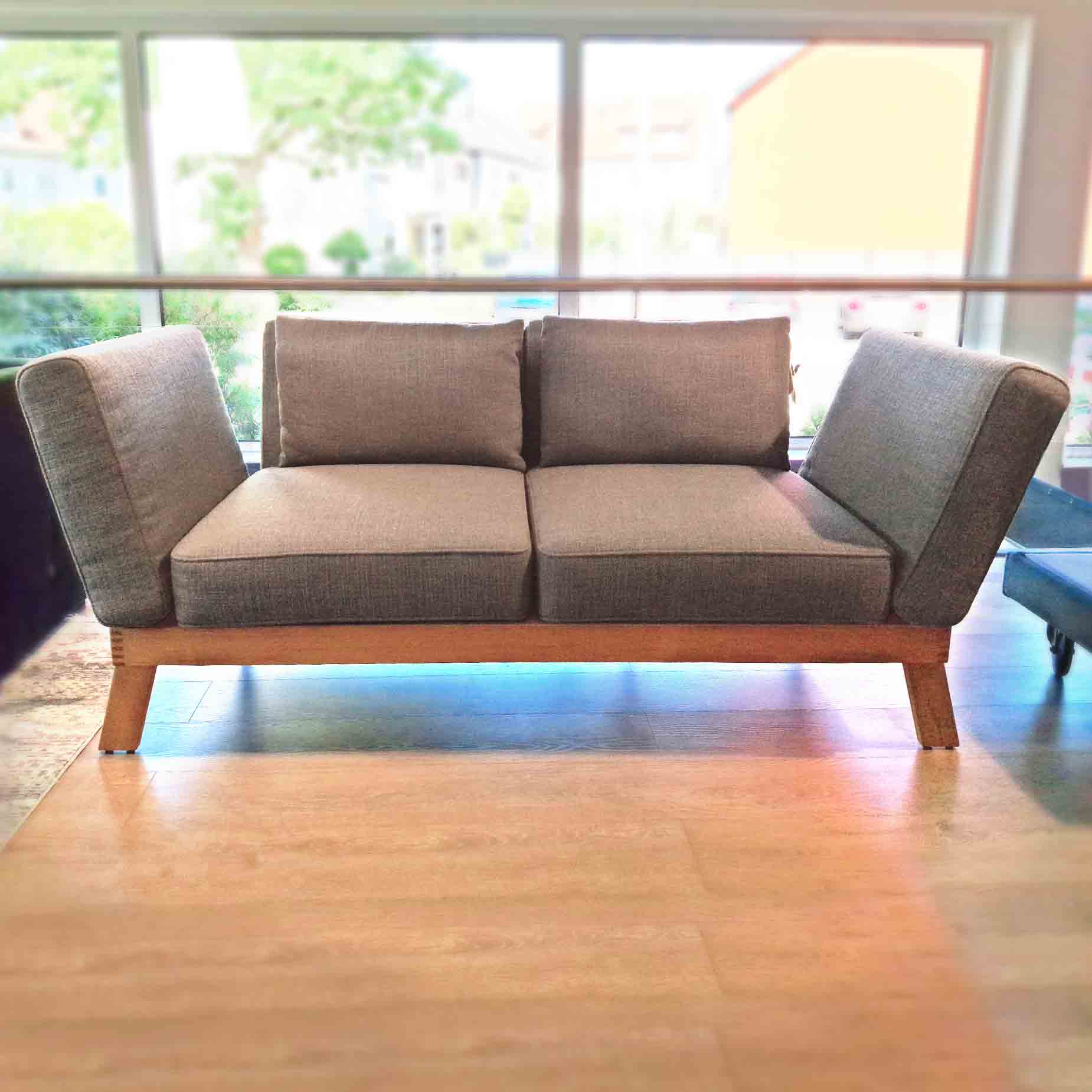 Sofa von brühl mit klappbaren Armlehnen und Holzgestell.