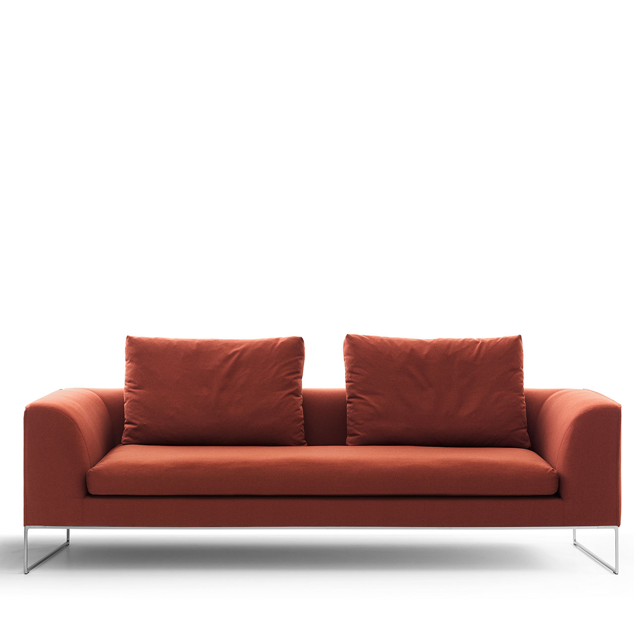 Rotes Sofa auf Chromkufen mit durchgehendem Sitzkissen und zwei Rückenkissen